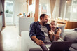 © Geber86 - Father and daughter laughing on sofa with laptop at home