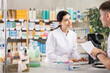 © JackF - In drug store, girl at counter with computer sells pills and ointments to young male customer, offer pills and consulting guy about doctors prescription. Everyday life at pharmacy, customer support