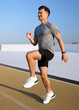 © muse studio - Energetic man training with high knees on an outdoor athletic track under a bright clear blue sky in daytime