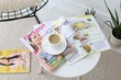 © New Africa - Lifestyle magazines and cup of coffee on white table indoors, closeup