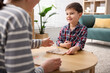 © New Africa - Mother and her happy son playing with educational toys at wooden table indoors, closeup