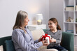 © New Africa - Little girl greeting her grandmother with gift indoors