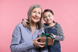 © New Africa - Little girl greeting her grandmother with gift on pink background
