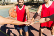 © AntonioDiaz - Basketball players stacking hands for teamwork, unity, and collaboration on outdoor court during game