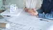 © volha_r - Architects discussing building plans, reviewing blueprints and architectural models, brainstorming design ideas for a new residential or commercial construction project