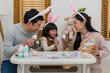 © geargodz - father, mother and daughter wearing bunny ears holding colorful egg  together at home on easter day. happy family holiday activity concept