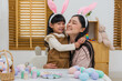 © geargodz - happy preschool child girl and mother hugging together while celebrating Easter day with colorful eggs on table at home