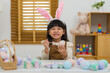 © geargodz - happy preschool child girl wearing bunny ears painting and decorating colorful egg at home on easter day