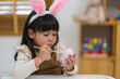 © geargodz - preschool child girl wearing bunny ears painting and decorating colorful egg at home on easter day