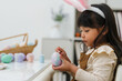 © geargodz - preschool child girl wearing bunny ears painting and decorating colorful egg at home on easter day