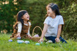 © geargodz - two happy child girl playing together and hunting for Easter eggs into basket on green grass in garden