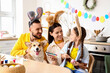 © Pixel-Shot - Happy parents with their little daughter and Corgi dog painting Easter egg in kitchen
