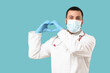 © Pixel-Shot - Young happy male doctor in protective mask with stethoscope showing heart gesture on blue background. World Health Day