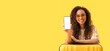 © Pixel-Shot - Young African-American woman with mobile phone and suitcase on yellow background with space for text. Travel concept