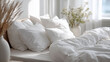 © glowcharmy - Clean unmade bed with white linen and a small green plant