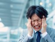 © Jumpei - ビジネスの悩みや過労によるストレスで激しい頭痛に耐えながら頭を抱えるビジネスマン