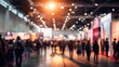 © IR-Creative - Blurred crowd of people walking through a large exhibition hall with bright lights