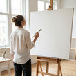 © Cihat - Female Artist Painting Blank Canvas on Wooden Easel in Bright Minimal Art Studio with Natural Light