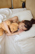 © Blue Jean Images - A girl sleeping in bed with a toy bear in her arms