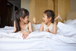 © Blue Jean Images - Sisters lying on bed, talking