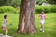 © Blue Jean Images - Two girls chasing each other around a huge tree