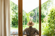© Westend61 - Back view of senior man wearing straw hat on terrace enjoying his garden