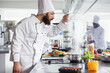 © DC Studio - Professional chef in uniform tasting a savory sauce from a pan on the stove, ensuring the perfect balance of flavors. Delicious dish simmers on the stovetop at a modern restaurant kitchen counter.