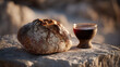 © KristinaEjevika - Rustic bread loaf and clay cup of red wine on limestone surface in warm sunrise light for biblical communion concept