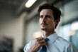 © Microstocke - Blurred Businessman adjusting tie, focused man in office, professional attire, determined look