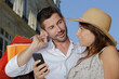 © auremar - couple in the street with shopping bags looking at smartphone