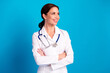 © deagreez - Confident female doctor stands with arms crossed wearing a white coat and stethoscope against a bright blue background ready to provide professional medical care