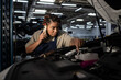 © Bliss - Young African American female mechanic working on car and talking on phone in garage