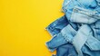 © Ali - Pile of denim jeans on vibrant yellow background