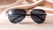 © Helois - Aviator Sunglasses on Soft Fabric Surface.