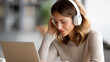 © Nataliya - Defocused unrecognizable woman wearing headphones on a video call while working from home on a laptop, remote work, distance education, webinar concept, with copy space