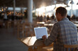 © sam richter - A lone professional works quietly on a laptop inside a warmly lit restaurant with beautiful blurred background.
