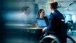 © SHI - a female manager with a laptop is talking to two other business people in a modern office meeting room. one of them is sitting in a wheelchair