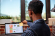 © DC Studio - Rearview closeup of african american manager placing a post it on his laptop, preparing for company presentation. Black male researcher sitting at office desk and using sticky notes for reminders.