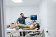 © Jordi Mora - Physiotherapist performing an ultrasound scan on a female patient's knee in a clean clinic, identifying musculoskeletal issues for diagnosis