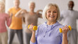 © Prostock-studio - Seniors participate in a fitness class, lifting weights while following an instructor. The atmosphere is lively as they focus on their exercise routine. Everyone is engaged and smiling.