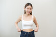 © KMPZZZ - Shape slender, thin waist, slim fit asian young woman, showing body shape her weight loss, happy wearing in big, large or oversize jeans, excess lose by diet and exercise. Healthy lifestyle concept