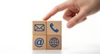 © MdMonsurAli - Hand pointing at wooden blocks with contact us symbols on white background