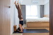 © leungchopan - Woman practicing yoga headstand pose at home