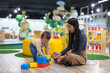 © leungchopan - Mum helping baby stack colorful blocks at playhouse