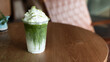 © pariwatpannium - Iced matcha latte layered with milk and topped with crunchy brown sugar waffle pieces