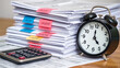 © Sean - A stack of tax documents tagged with urgent deadlines a calculator and a clock ticking down encapsulating the pressure of tax season
