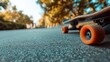 © Yanka - Skateboard wheels on textured asphalt sunlight vivid orange wheels with park backdrop, playful leisure mood, youth practice suggestion, lowangle framing, strong color contrast, social outdoor energy