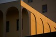 © Gaïan - Architecture minimaliste arcs répétés ombre longue bâtiment beige crépuscule