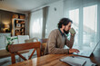 © Dusan - Man drinking coffee working on laptop from home