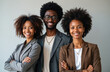 © Viktor - Three young professionals, one man, two women of color, stand together. Wear business attire, smile confidently. Diverse appearances, modern hairstyles suggest forward-thinking company culture. Team